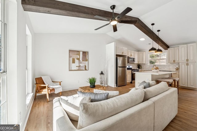 living room with ceiling fan, lofted ceiling with beams, and light wood-type flooring