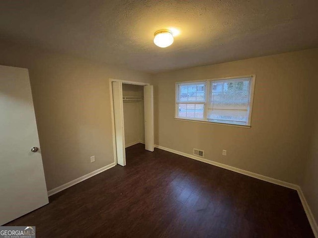 unfurnished bedroom with dark hardwood / wood-style floors, a closet, and a textured ceiling