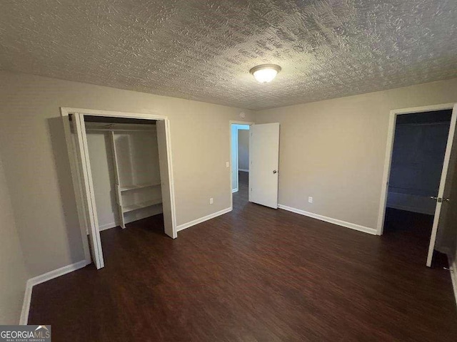 unfurnished bedroom with dark wood-type flooring, a textured ceiling, and a closet