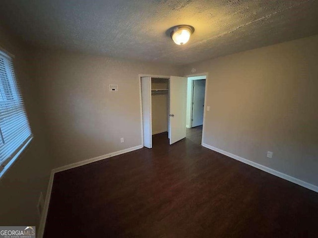 unfurnished bedroom featuring dark hardwood / wood-style floors, a closet, and a textured ceiling