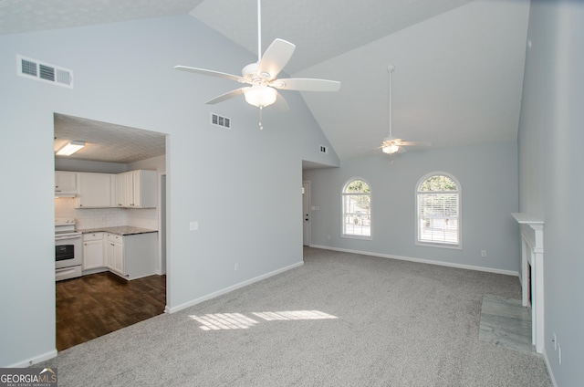 unfurnished living room with dark colored carpet, high vaulted ceiling, and ceiling fan