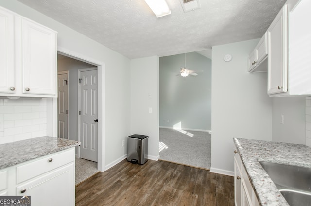 kitchen featuring tasteful backsplash, light stone countertops, and white cabinets