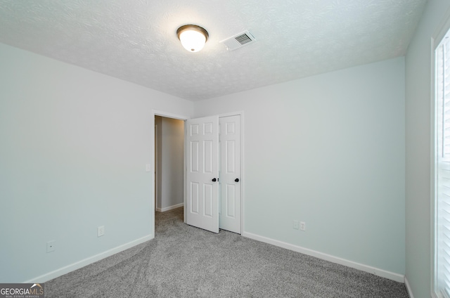 spare room with light colored carpet and a textured ceiling