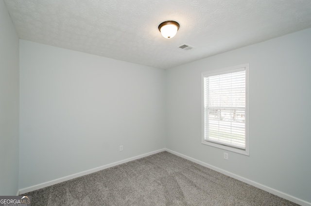 carpeted empty room featuring a textured ceiling