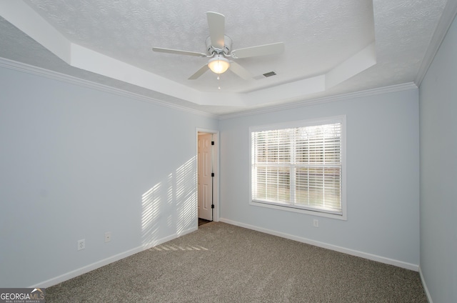 carpeted empty room with a raised ceiling, ceiling fan, ornamental molding, and a textured ceiling