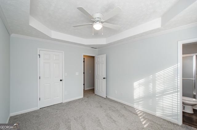 unfurnished bedroom featuring a tray ceiling, light carpet, and a textured ceiling