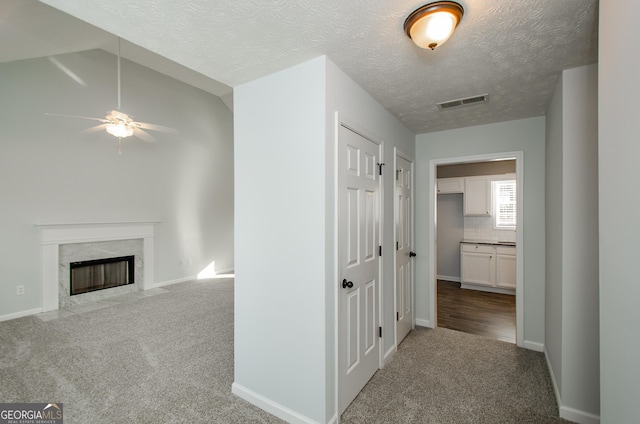 hall with vaulted ceiling, carpet flooring, and a textured ceiling