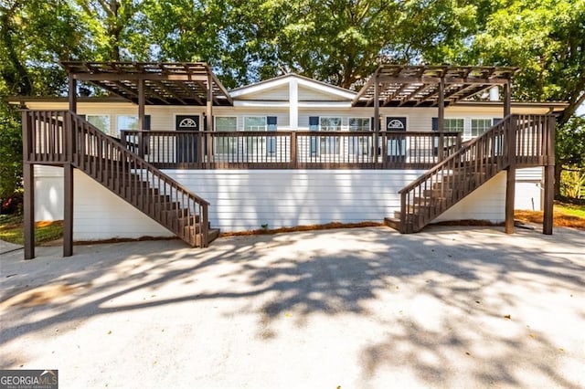 rear view of house featuring a wooden deck and a pergola