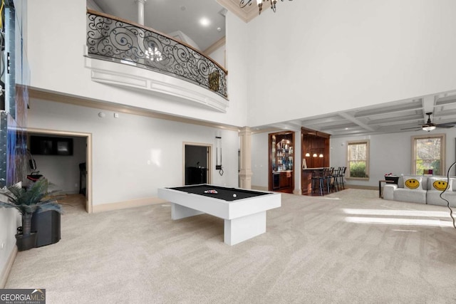 game room featuring light colored carpet, indoor bar, a towering ceiling, ceiling fan, and decorative columns