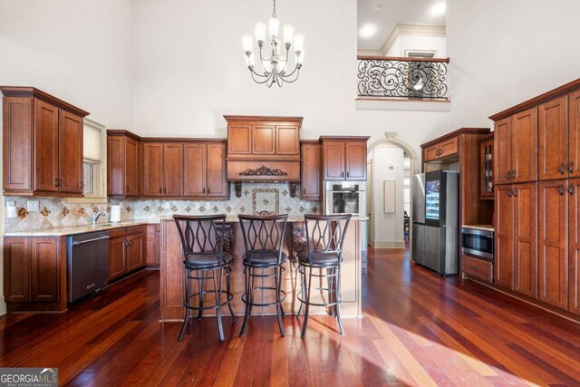 kitchen featuring decorative light fixtures, dark hardwood / wood-style floors, a high ceiling, and appliances with stainless steel finishes