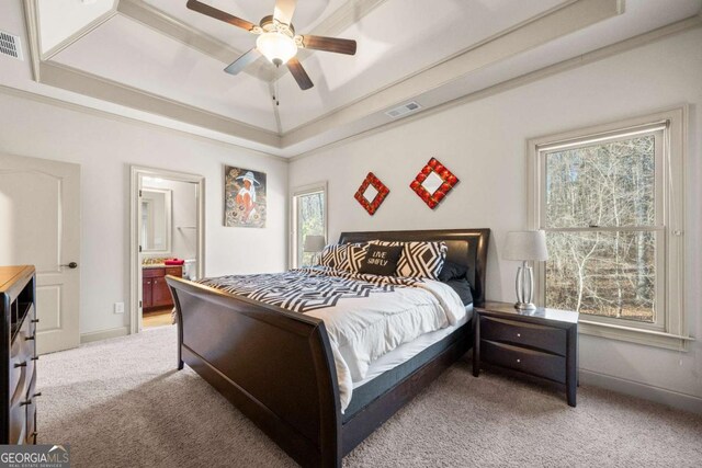 carpeted bedroom with ceiling fan, ensuite bath, and a raised ceiling