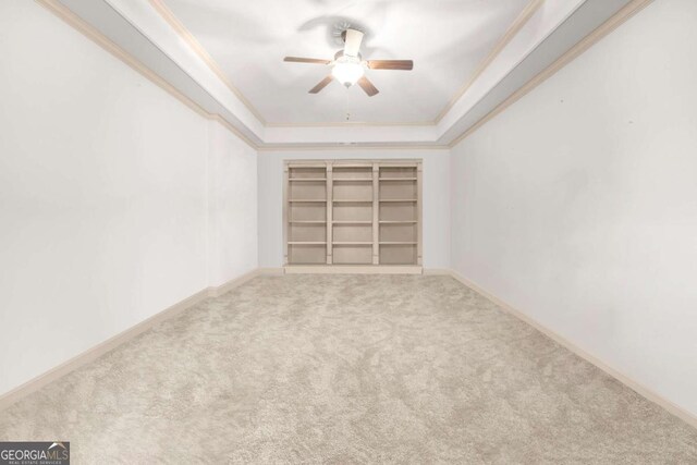 unfurnished room with ornamental molding, a raised ceiling, ceiling fan, and carpet flooring