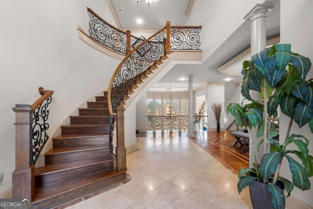 staircase with decorative columns, crown molding, and a high ceiling