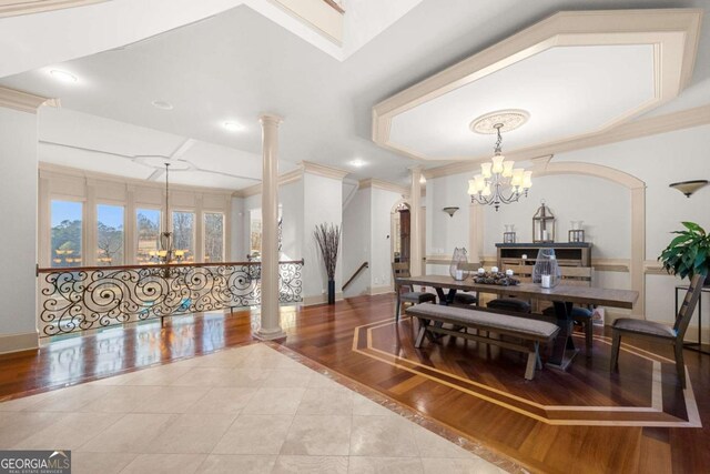 tiled dining area with ornate columns, ornamental molding, and a chandelier