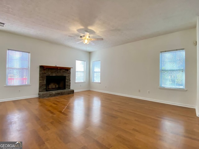 4299 High Country Dr, Douglasville, GA 30135 - unfurnished living room with hardwood / wood-style flooring, a stone fireplace, a textured ceiling, and ceiling fan