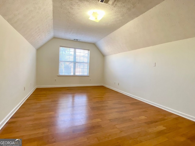 4299 High Country Dr, Douglasville, GA 30135 - additional living space featuring vaulted ceiling, hardwood / wood-style floors, and a textured ceiling