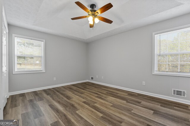 unfurnished room featuring ceiling fan, a healthy amount of sunlight, dark hardwood / wood-style flooring, and a textured ceiling