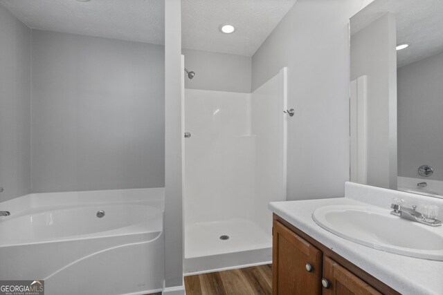 bathroom with vanity, hardwood / wood-style floors, a textured ceiling, and separate shower and tub