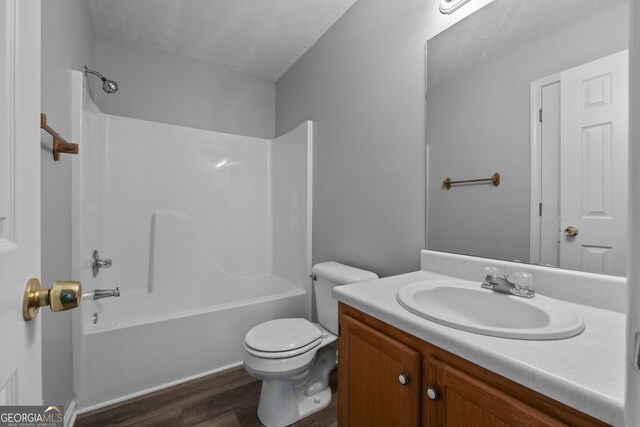 full bathroom featuring hardwood / wood-style floors, vanity, a textured ceiling, bathtub / shower combination, and toilet