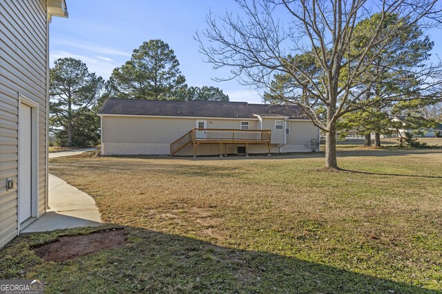 rear view of property featuring a wooden deck and a yard