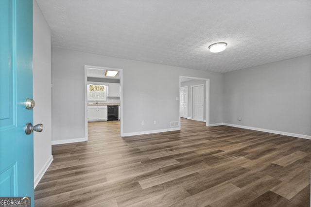 empty room with dark wood-type flooring, a textured ceiling, and wine cooler