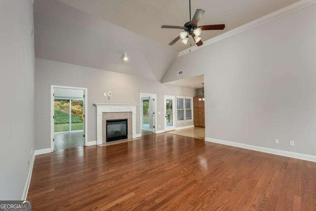 unfurnished living room featuring hardwood / wood-style flooring, high vaulted ceiling, a premium fireplace, and ceiling fan