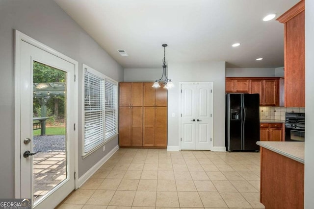 kitchen with pendant lighting, range, backsplash, light tile patterned flooring, and black fridge