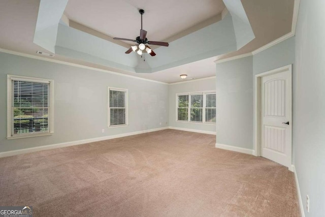 empty room featuring light colored carpet, ornamental molding, a raised ceiling, and ceiling fan