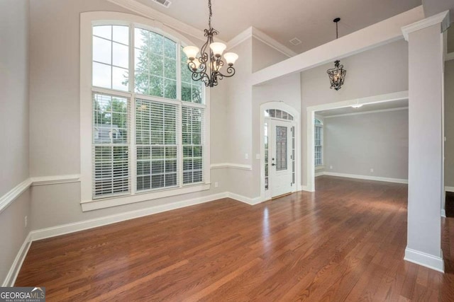 spare room featuring an inviting chandelier, a towering ceiling, dark wood-type flooring, and ornamental molding