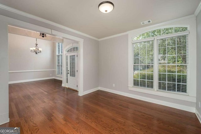 empty room featuring dark wood-type flooring, ornamental molding, and a chandelier