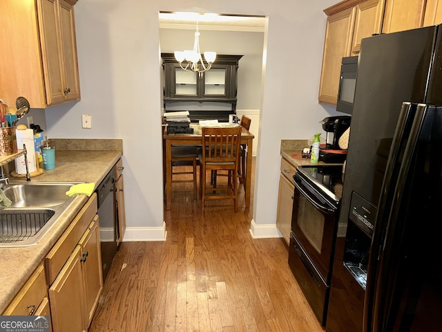 kitchen featuring sink, an inviting chandelier, crown molding, light hardwood / wood-style flooring, and black appliances