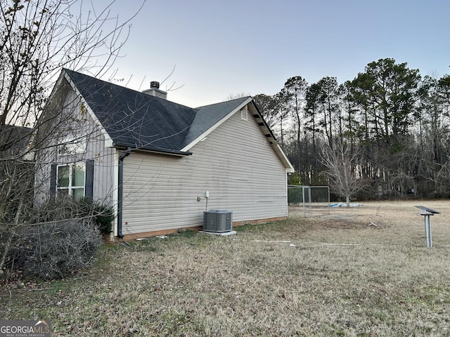 view of property exterior with central AC unit and a lawn