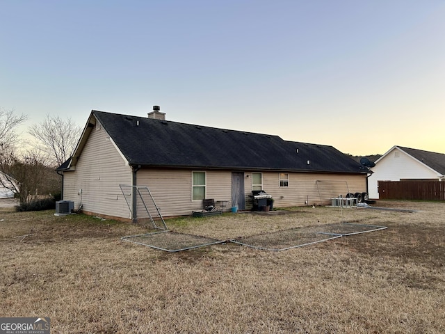 back house at dusk with a yard and central air condition unit