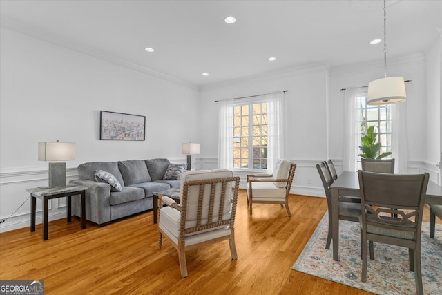 living room featuring crown molding, a wealth of natural light, and light wood-type flooring