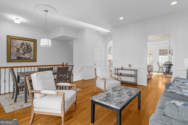 living room featuring crown molding, light hardwood / wood-style floors, and a chandelier