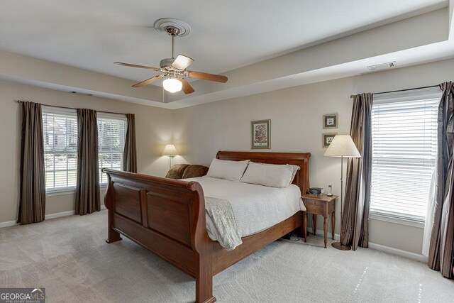 carpeted bedroom featuring ceiling fan and a tray ceiling