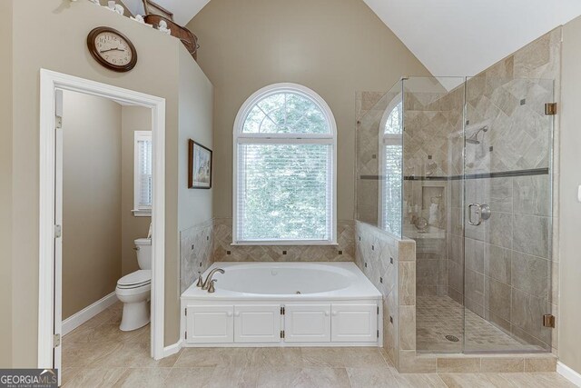 bathroom featuring shower with separate bathtub, lofted ceiling, tile patterned floors, and toilet