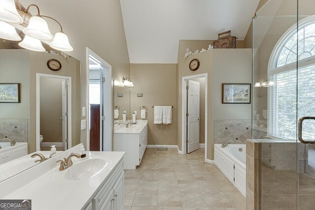 bathroom featuring a relaxing tiled tub, vanity, high vaulted ceiling, and toilet