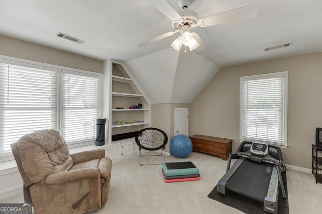 exercise room featuring vaulted ceiling, light carpet, ceiling fan, and built in shelves