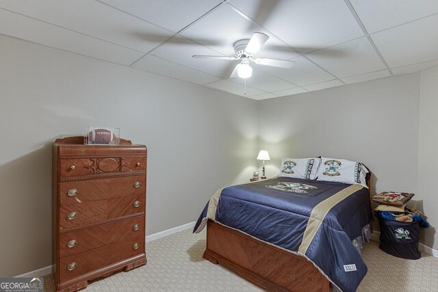 carpeted bedroom with ceiling fan and a drop ceiling