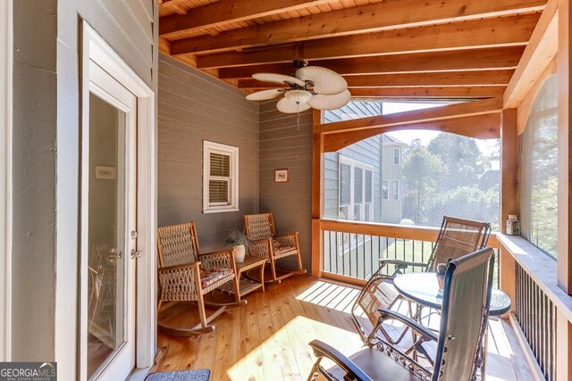 sunroom / solarium with wood ceiling, beam ceiling, and ceiling fan