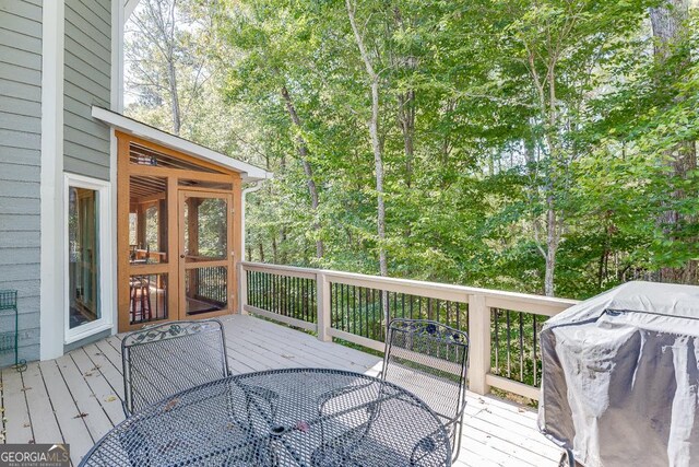 wooden deck with area for grilling and a sunroom