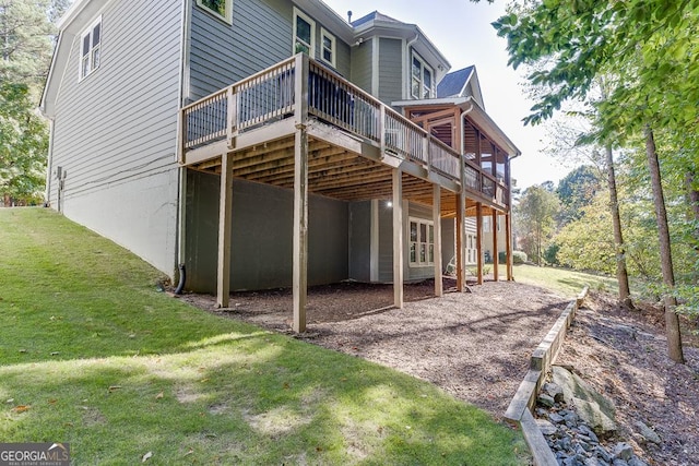 rear view of property with a wooden deck and a lawn