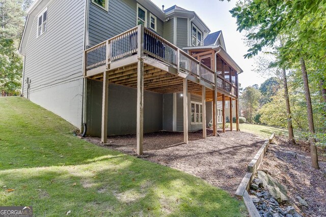 rear view of property with a wooden deck and a lawn