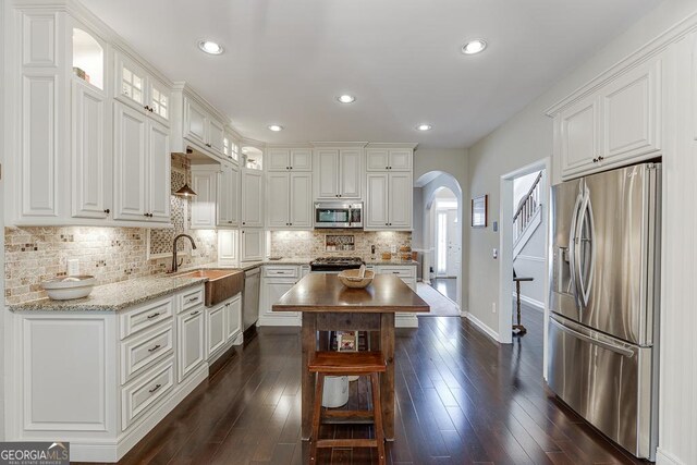 kitchen featuring sink, white cabinetry, tasteful backsplash, light stone counters, and stainless steel appliances