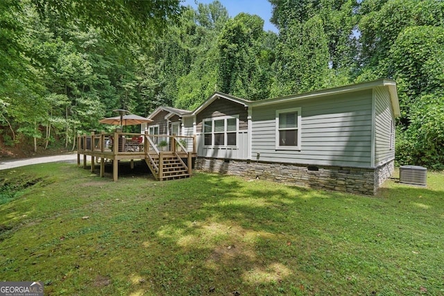 back of property with a wooden deck, a yard, and central AC unit