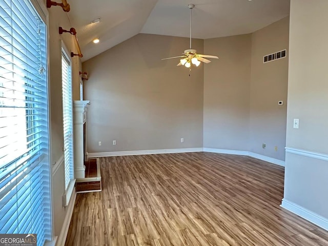 unfurnished living room with baseboards, visible vents, a ceiling fan, wood finished floors, and vaulted ceiling