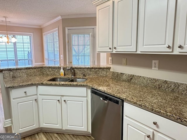 kitchen featuring light wood finished floors, stainless steel dishwasher, ornamental molding, a sink, and a textured ceiling