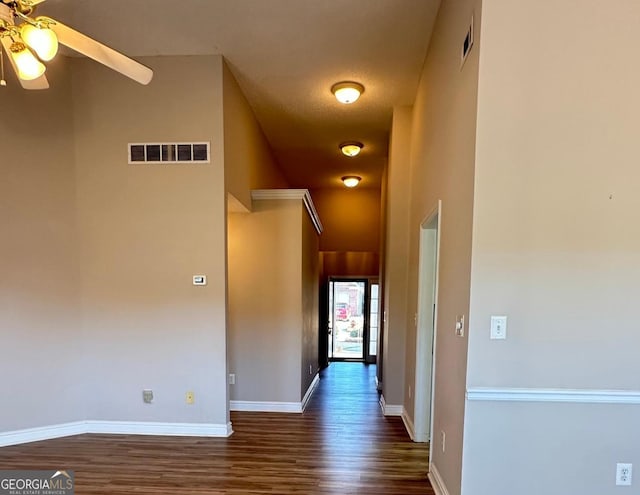 hall with dark wood-style floors, visible vents, and baseboards