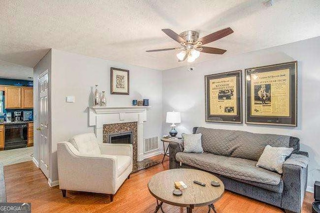 living room featuring ceiling fan, light hardwood / wood-style floors, and a textured ceiling